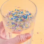 A glass of water containing beads of plastic ,plastic droplets