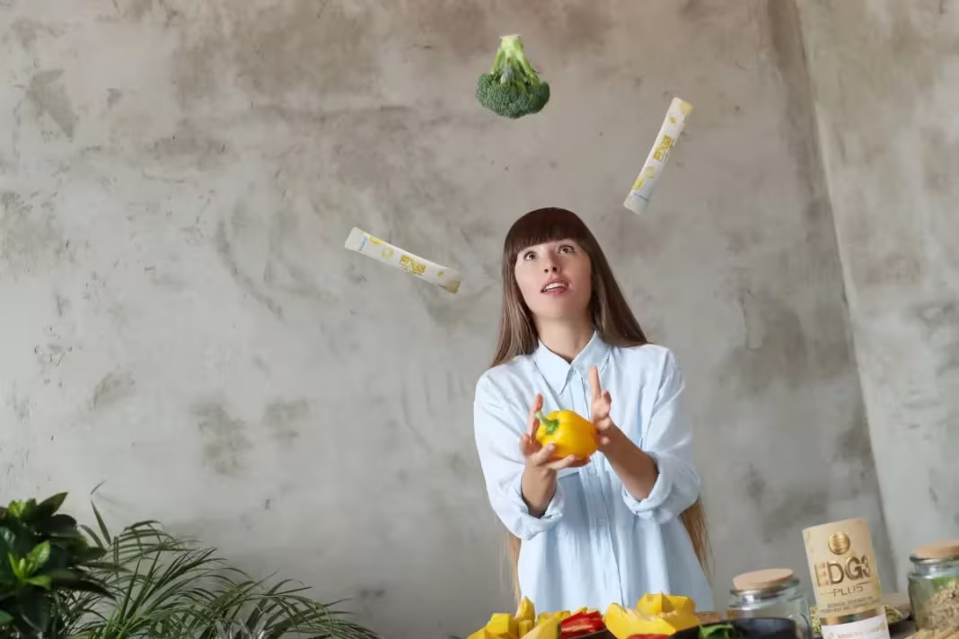 Woman who enjoys a plant-based diet juggling EDG3 Plus packets with broccoli and bell pepper 