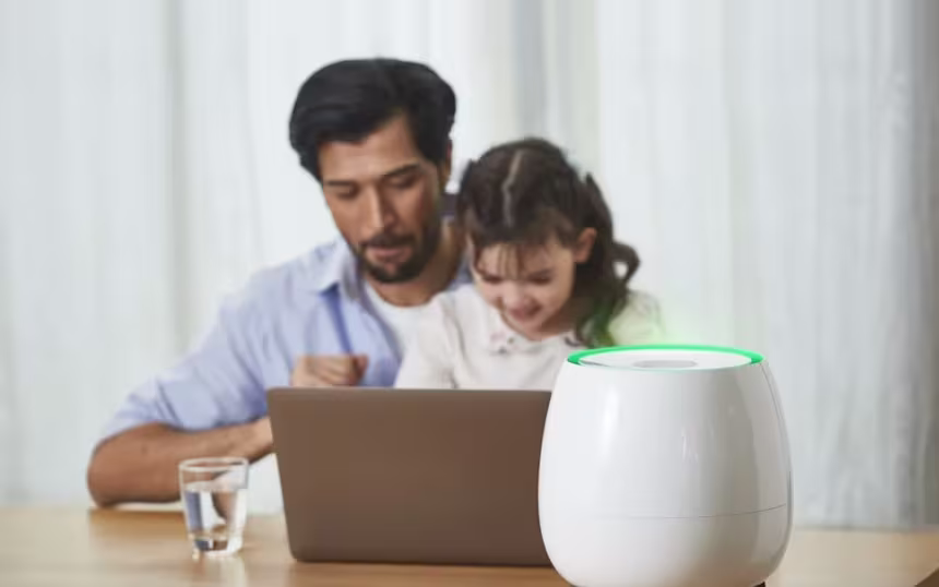A father and his daughter sit at a table with a laptop, while HomePure Zayn ensures safe and clean indoor air