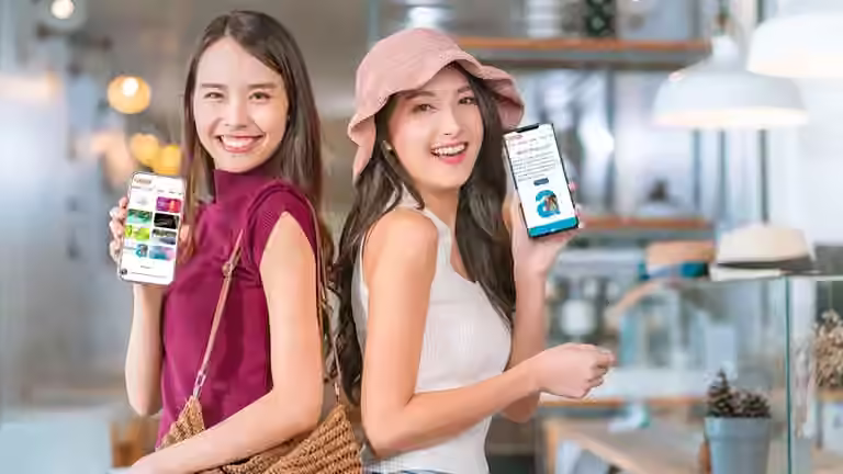 2 women smiling showing qbuzz on their mobile phones