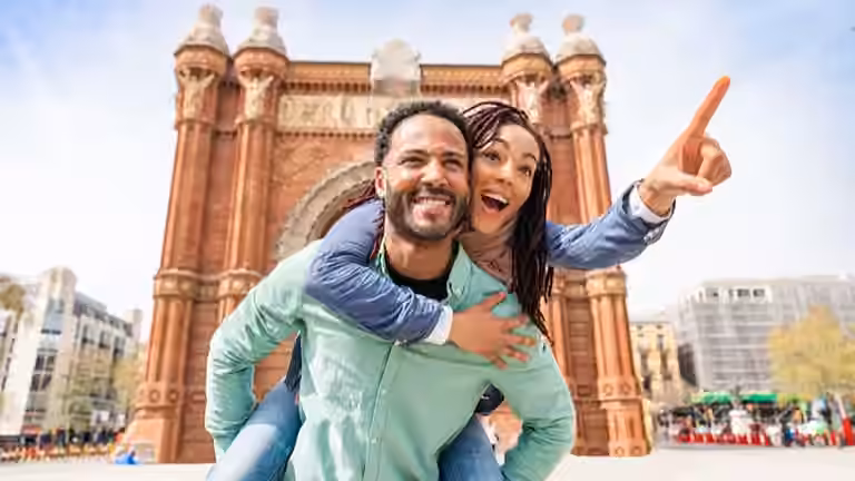 Man giving woman a piggy back ride in Europe while on a trip booked through a QVI holiday membership