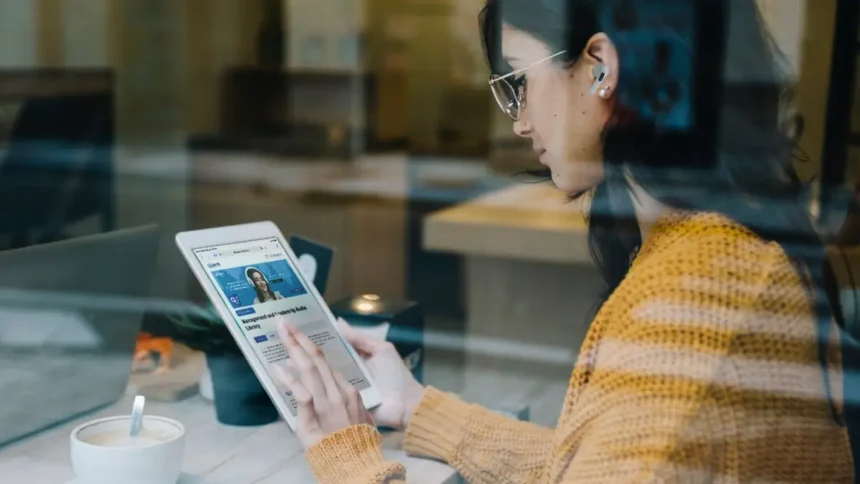 Caucasian girl engaging in hybrid learning with qLearn's management and leadership audio library on her tablet while she's at a cafe