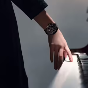 Woman's hand on the piano; there is a Bernhard H. Mayer Alto Ceramic watch on her wrist